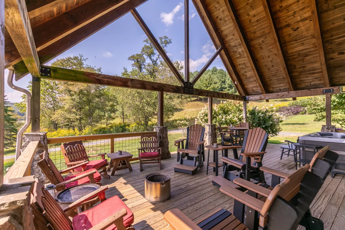 An inviting outdoor setting featuring adirondack chairs surrounding a fire pit, all set against a backdrop of rolling landscape and open sky. The scene suggests communal gathering, relaxation, and evenings spent under the stars.