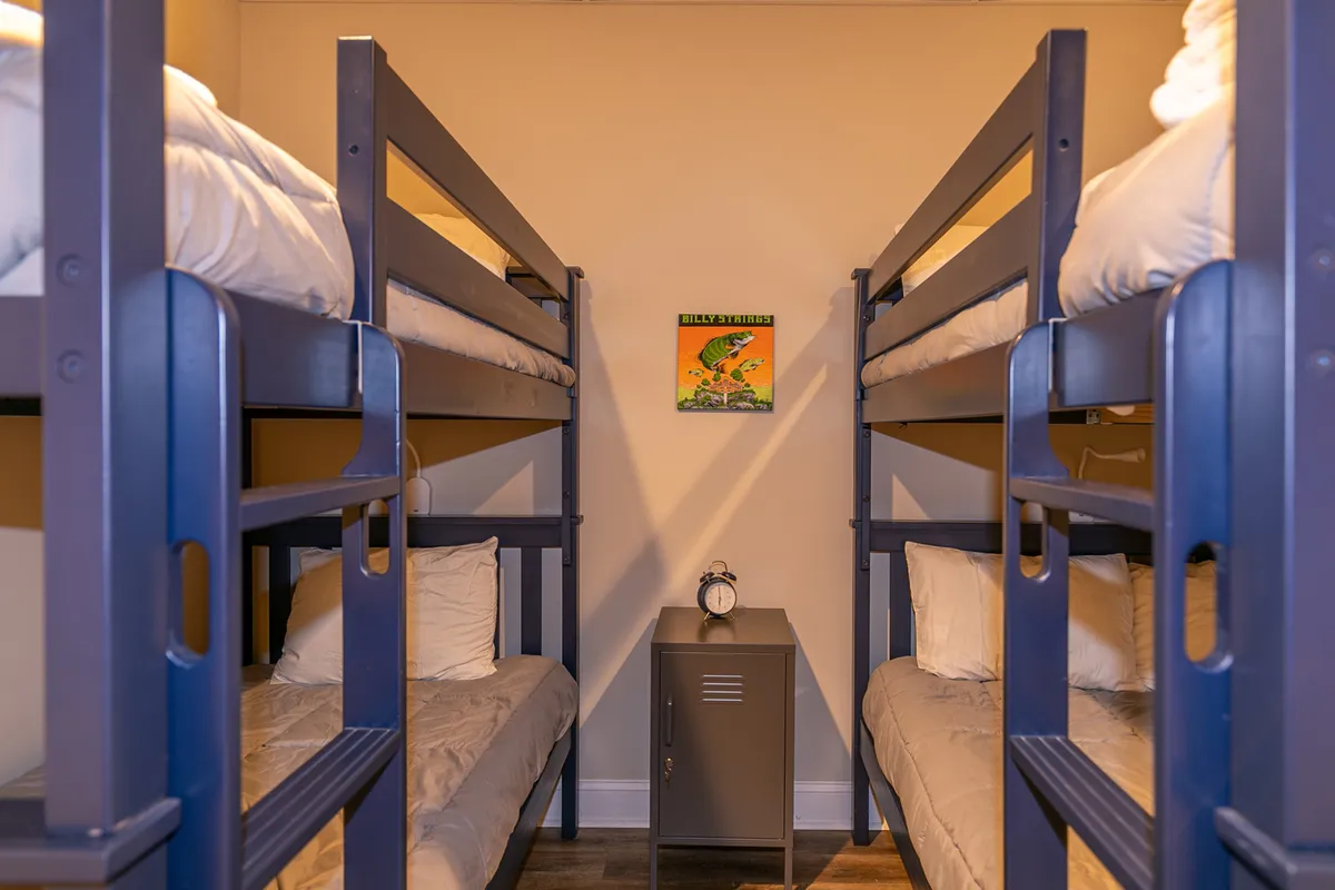 A playful and cozy bunk room featuring sturdy bunk beds, a nightstand with a small clock, and cheerful wall art. The scene suggests a fun, kid-friendly hideaway perfect for bonding and late-night chats.
